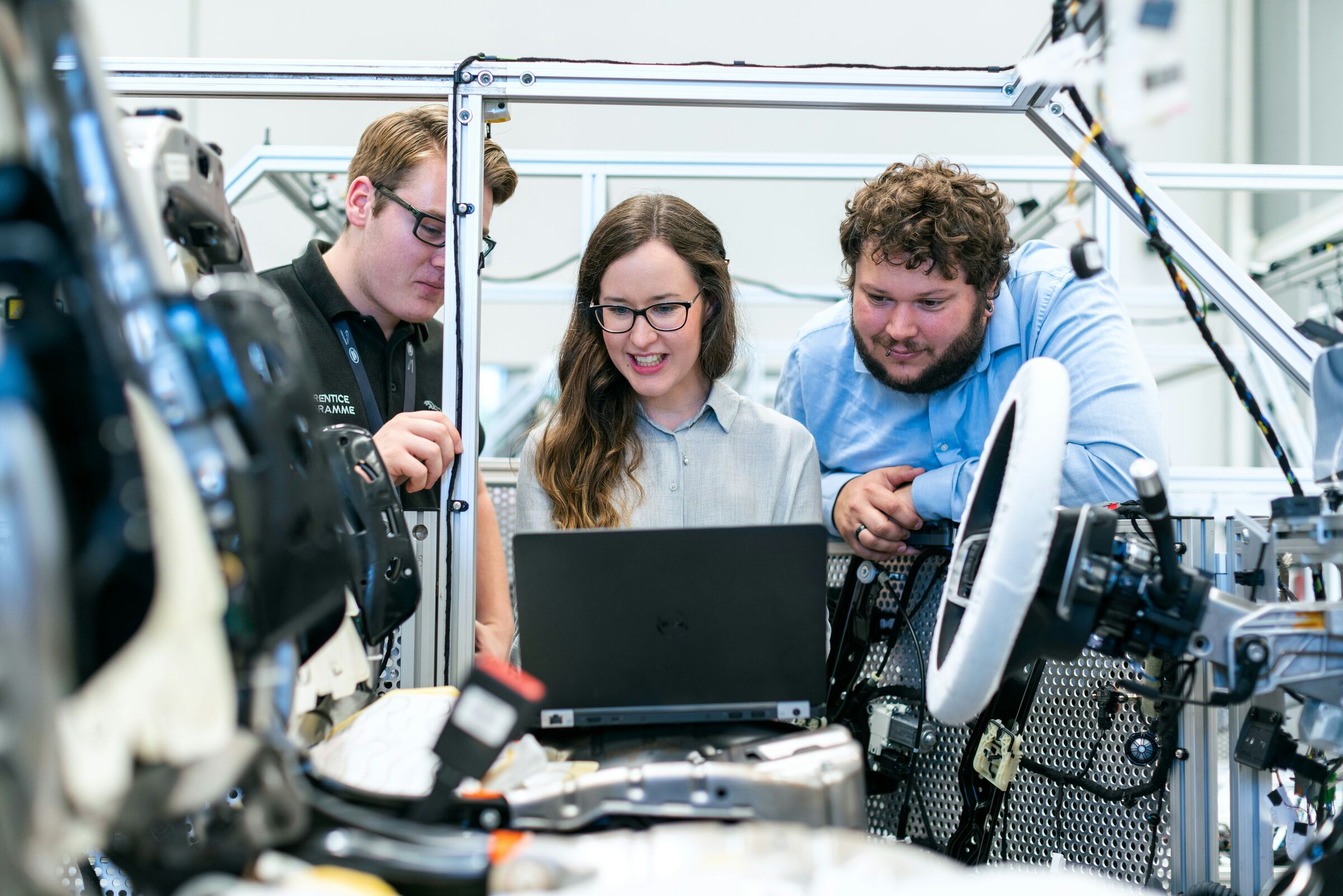 Engineering team reviewing work on a laptop in an assembly workspace